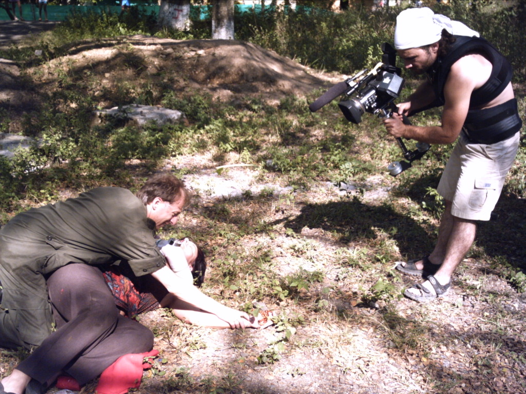 DIRECTOR SPIROS STATHOULOPOULOS OPERATES HANDHELD CAMERA DURING THE FIELD SCENE.
